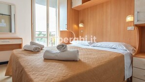 Une chambre d’hôtel avec un lit, une table de chevet, un miroir et une fenêtre donnant sur un paysage agréable.