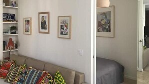 Ein Wohnzimmer mit einer Couch, bunten Kissen und drei gerahmten Kunstwerken an der Wand.