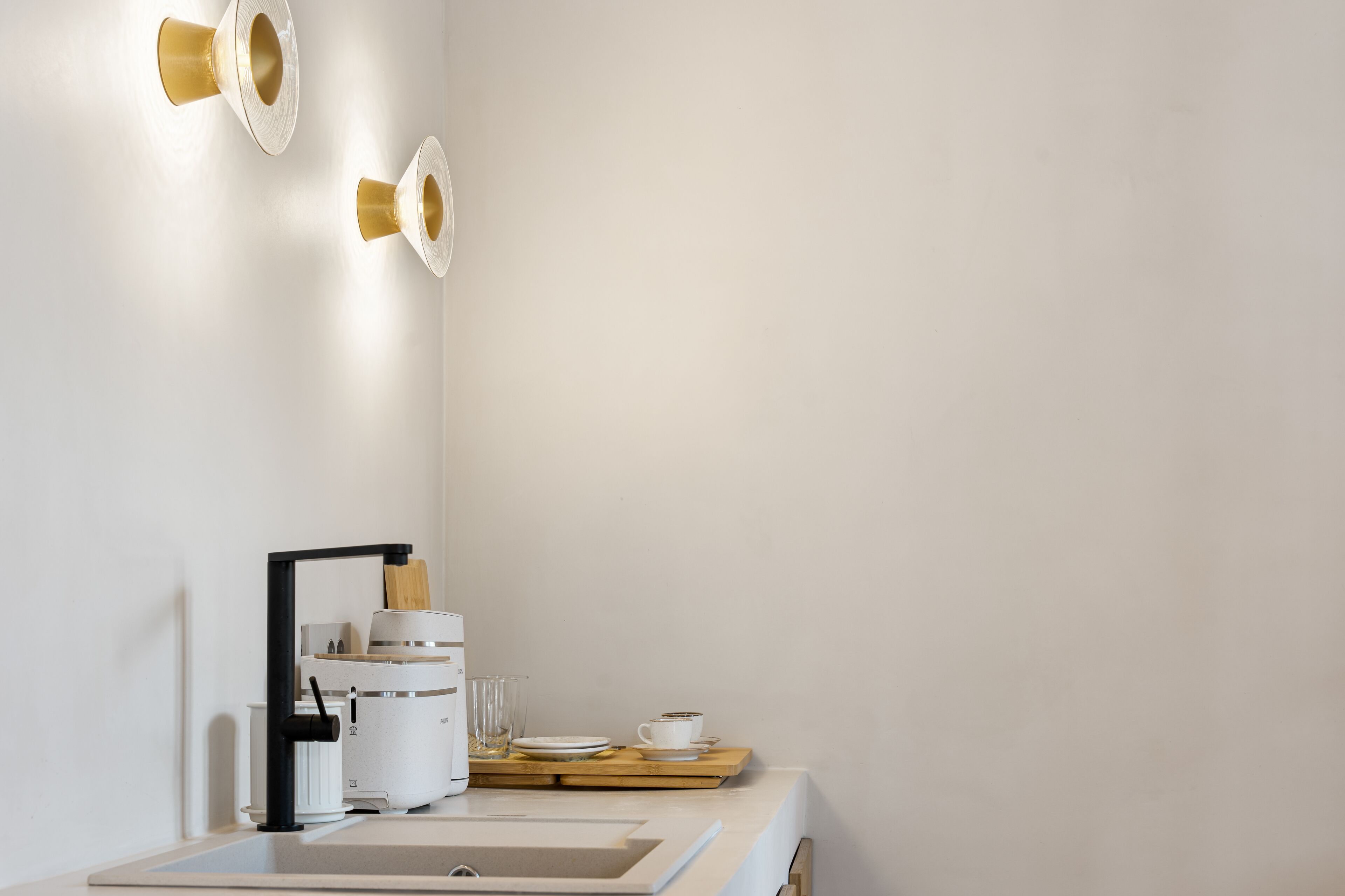 A modern kitchen with a white countertop, a coffee machine, and a sink.
