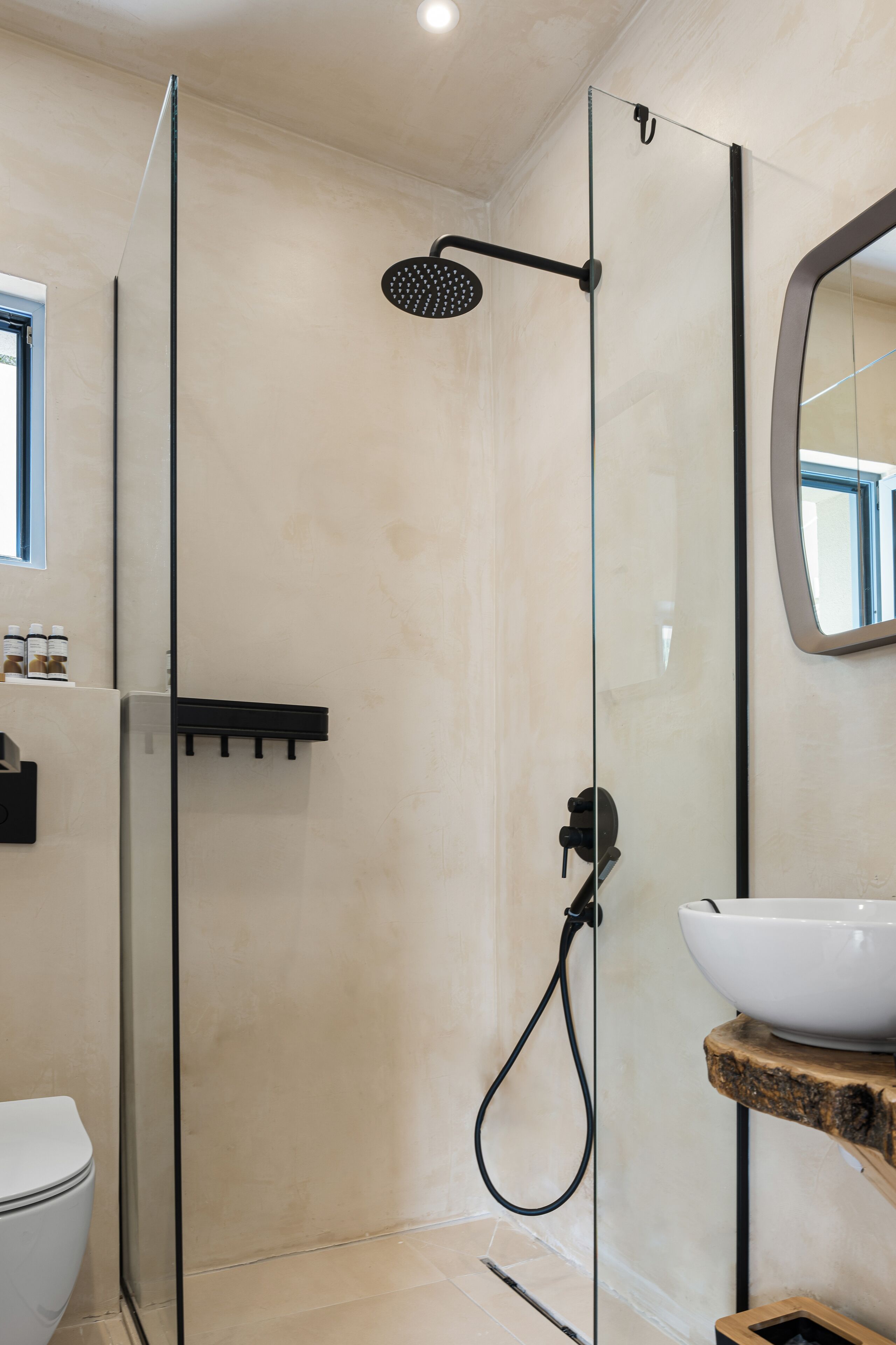 A modern bathroom with a glass-enclosed shower, a white sink, and a mirror.