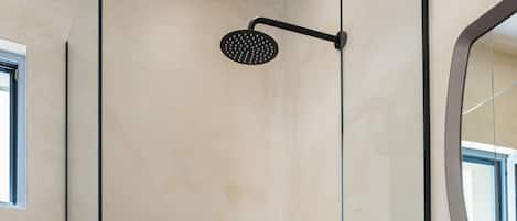 A modern bathroom with a glass-enclosed shower, a white sink, and a mirror.