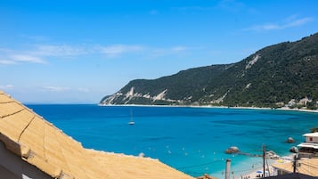 Vista costera con playa, mar azul cristalino y montañas al fondo.
