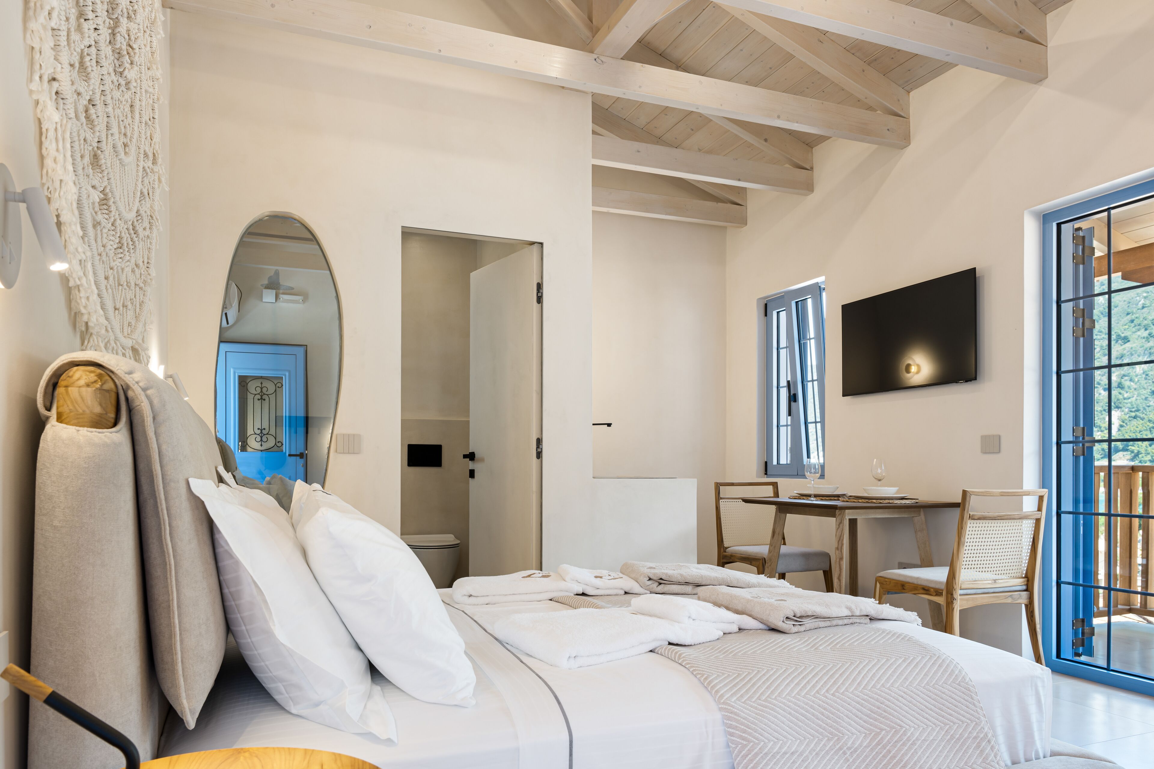 A bedroom with a large bed, a desk, and a television.