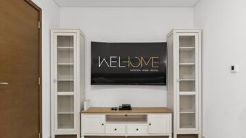 Una habitación con un televisor montado en la pared, un mueble bajo de madera y dos estanterías abiertas a cada lado.