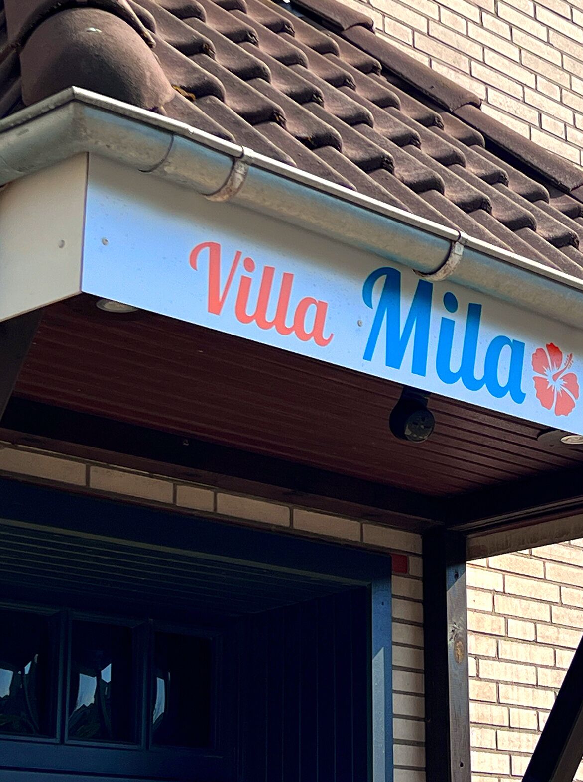A sign for "Villa Mila" with a floral logo.