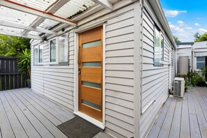 Cozy home with a covered porch and wooden deck, featuring a front door with a glass panel.