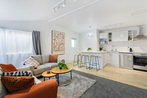 Relax in this stylish living space with a sofa, coffee table, and kitchen area featuring a bar with stools.