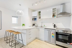 Enjoy cooking in this well-equipped kitchen with a stainless steel oven, bar stools, and pendant light.