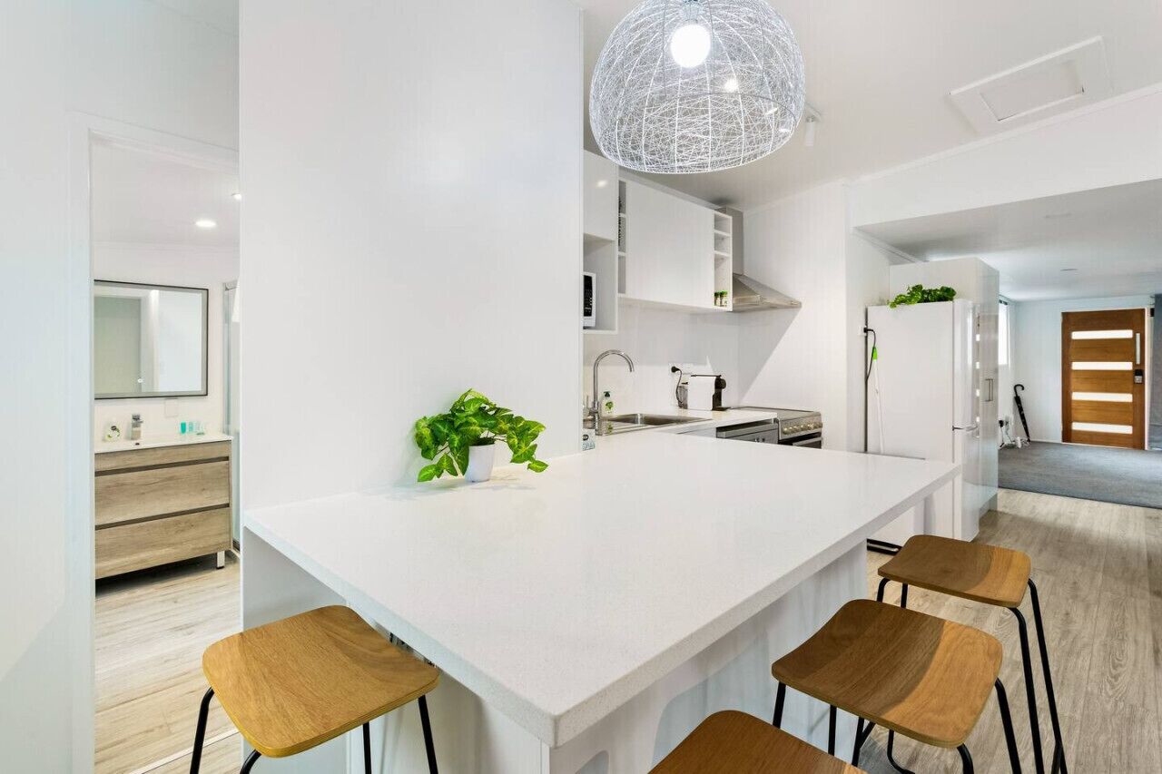 Une cuisine moderne dotée d’un îlot central, de tabourets de bar et d’un luminaire suspendu.