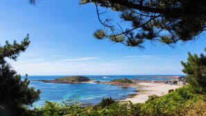 A coastal landscape with clear blue waters, sandy beach, and dense greenery. - VVF Côte de Granit Rose à Trébeurden (Trébeurden)