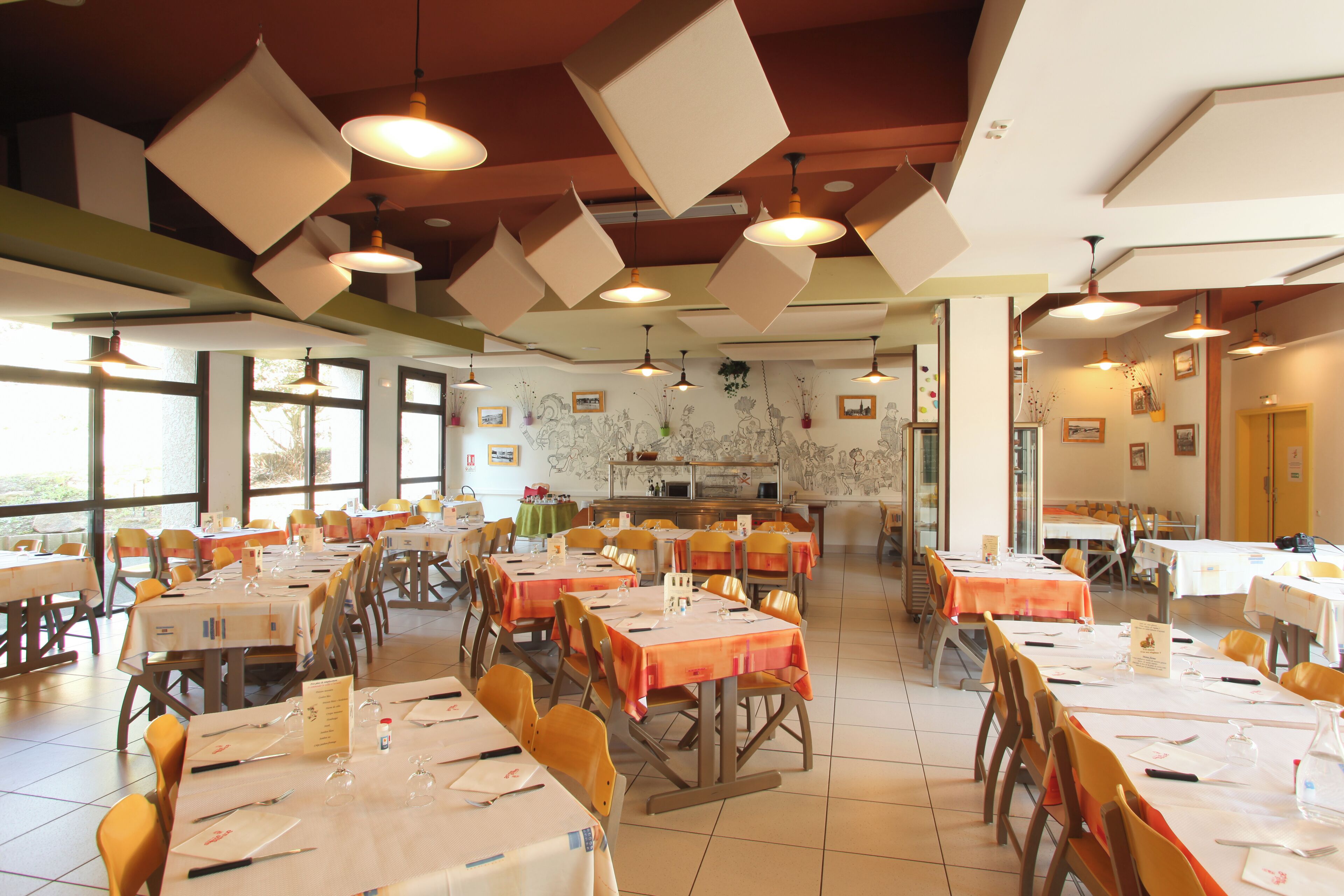 A dining area with tables set for meals, chairs, and hanging pendant lights.