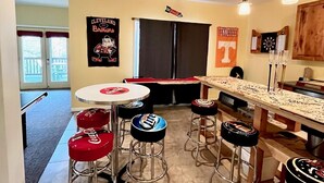 A bar area with stools, a bar counter, and a refrigerator. There are posters on the wall, including one for Tennessee. - Pines Cabin on Norris Lake (Tazewell)