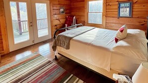 A wooden cabin bedroom with a bed, a ceiling fan, and a window. - Pines Cabin on Norris Lake (Tazewell)