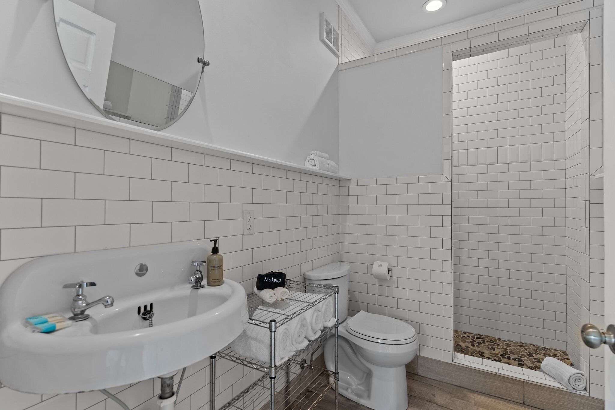 A bathroom with a white sink, toilet, and shower area.