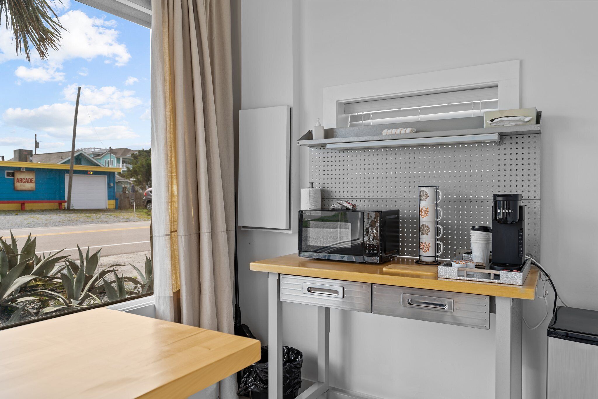 A compact kitchenette with a microwave, coffee maker, and storage shelves.