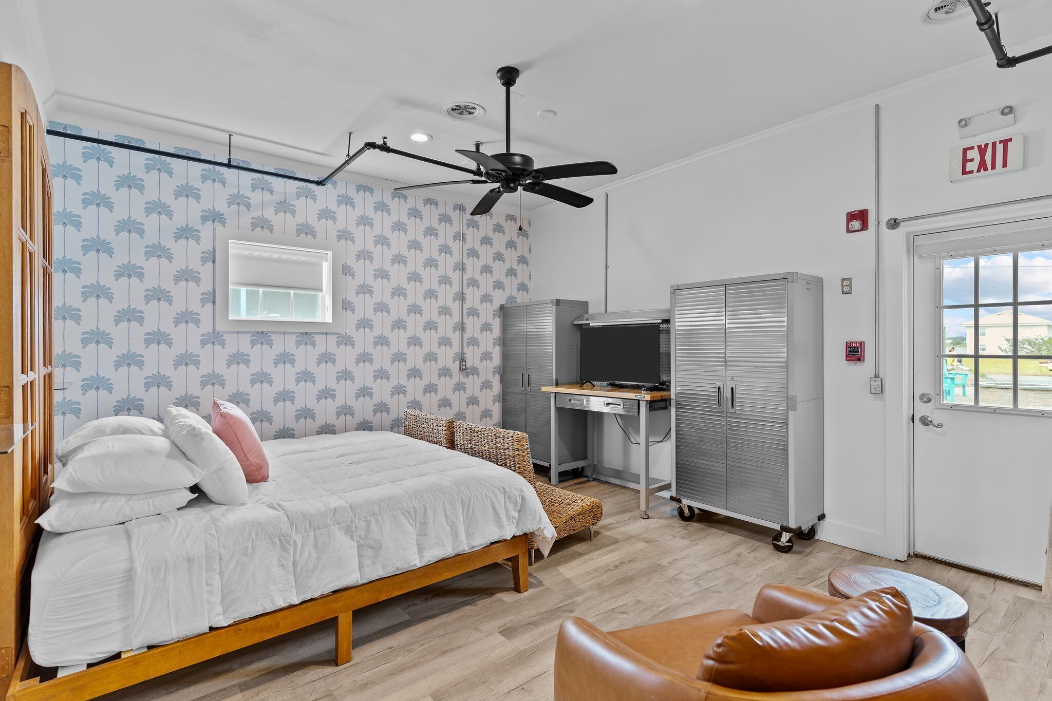 Une chambre à coucher comprenant un lit, un bureau, une armoire et un panneau indiquant la sortie.