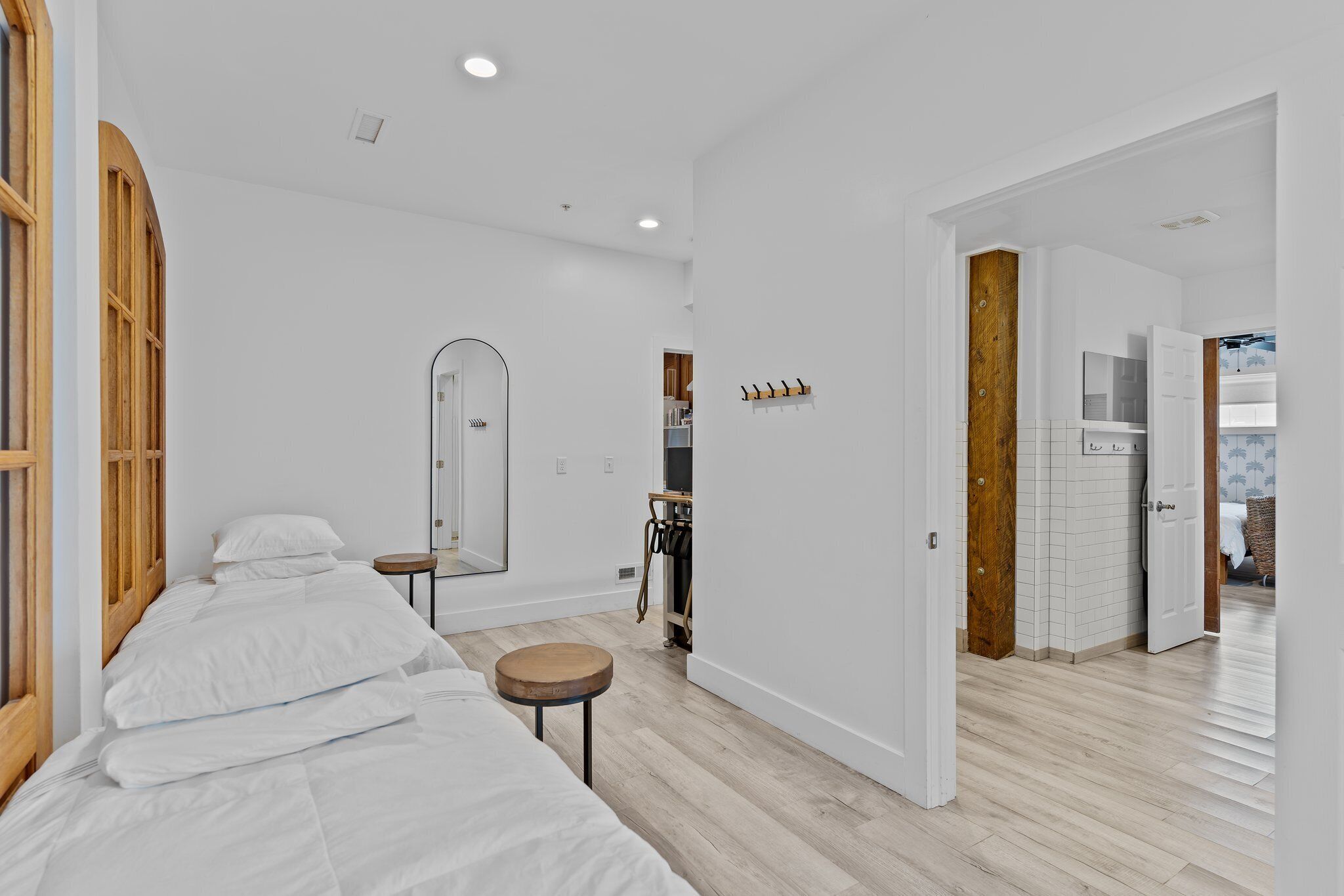 Une chambre d’hôtel moderne avec un grand lit, une petite table ronde, un miroir et une armoire en bois.