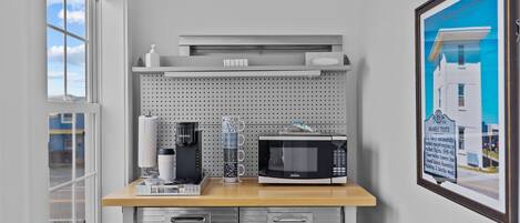 A kitchen with a microwave, coffee maker, and a framed picture on the wall.