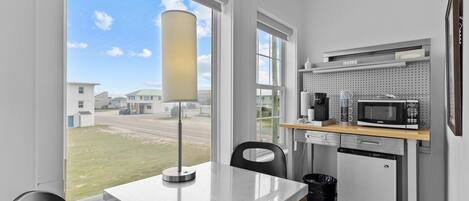 A compact kitchen with a dining area, a refrigerator, a microwave, and a coffee maker.