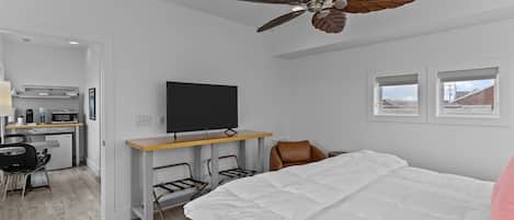 Une chambre d’hôtel moderne équipée d’un lit, d’un bureau avec un téléviseur à écran plat, d’un ventilateur de plafond et offrant une vue sur l’extérieur par une fenêtre.