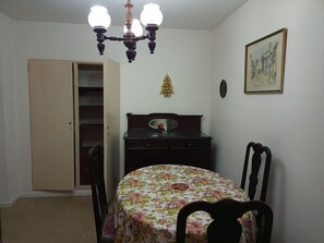 Un dormitorio con cama, cómoda, silla, armario, candelabro y un cuadro en la pared.