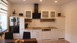 A modern kitchen with white cabinets, a black range hood, a microwave, a coffee maker, and a sink. - 25 Minuten vom Großen Goitzschesee Entfernt, Apartment für bis zu Vier Personen (Zörbig)