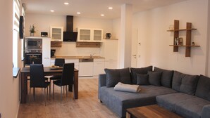 A modern living room with a grey sofa, a wooden coffee table, and a dining area with a table and chairs. - 25 Minuten vom Großen Goitzschesee Entfernt, Apartment für bis zu Vier Personen (Zörbig)