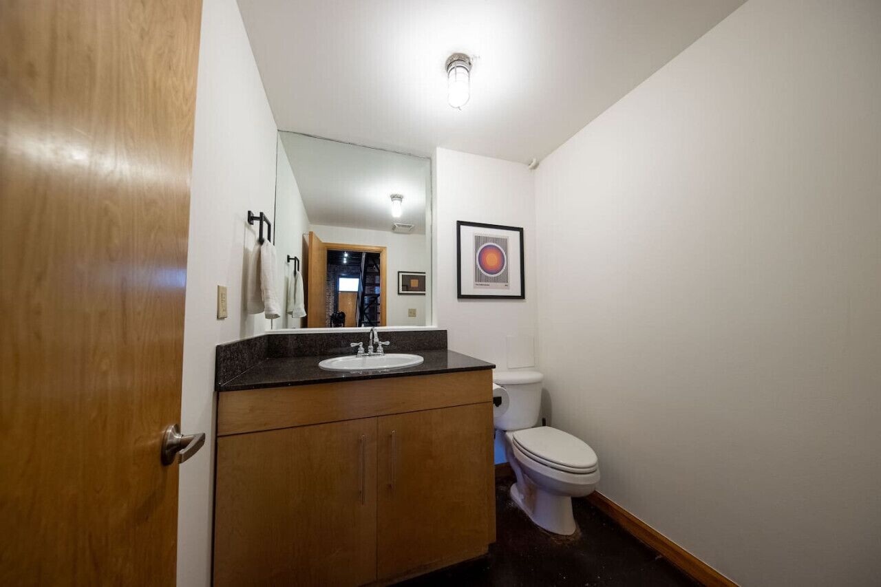 Une salle de bain avec un meuble-lavabo en bois, des toilettes blanches et un tableau encadré au mur.