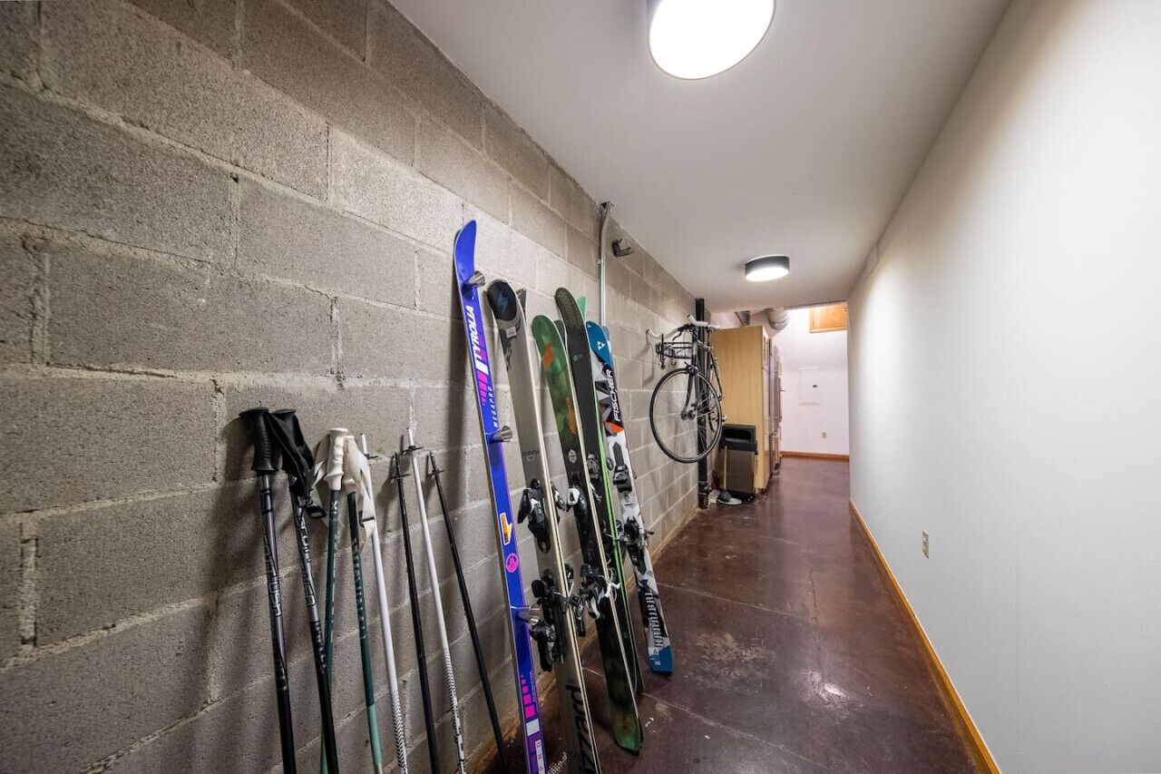 Een gang met ski's en stokken die tegen een bakstenen muur rusten.
