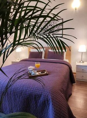Relax in this inviting bedroom with a large bed, a potted plant, and a convenient nightstand.