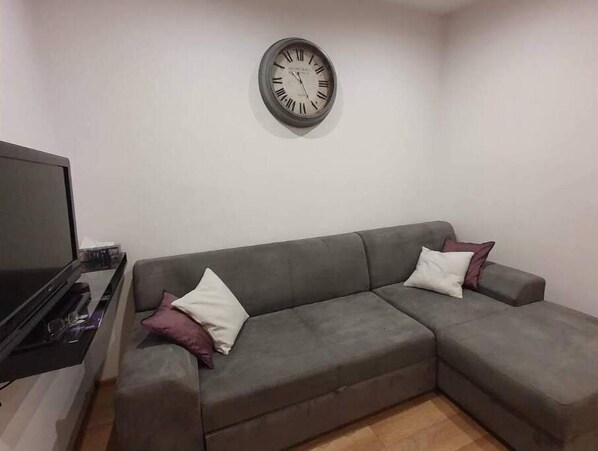 Relax in this stylish living room with a comfortable sofa, flat-screen TV, and a round wall clock.