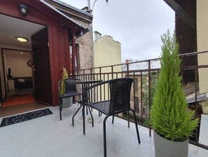 Enjoy the view from this balcony with a potted plant and two comfortable chairs.