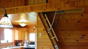 L’intérieur d’une cabane en bois comprend une cuisine, un coin repas et un escalier.