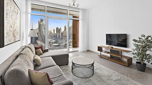 A modern living room with a large window, a sofa, a coffee table, a TV, and a plant.