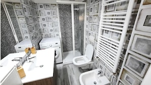 Une salle de bain au design moderne, avec un lavabo blanc, des toilettes et un espace douche agrémenté d’un mur carrelé.