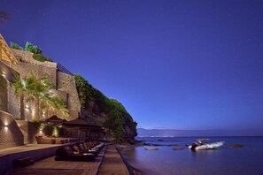 Relax on the beachfront deck with lounge chairs and umbrellas, steps leading down to the ocean.