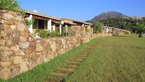 Fileira de edifícios com paredes de pedra e uma montanha ao fundo.