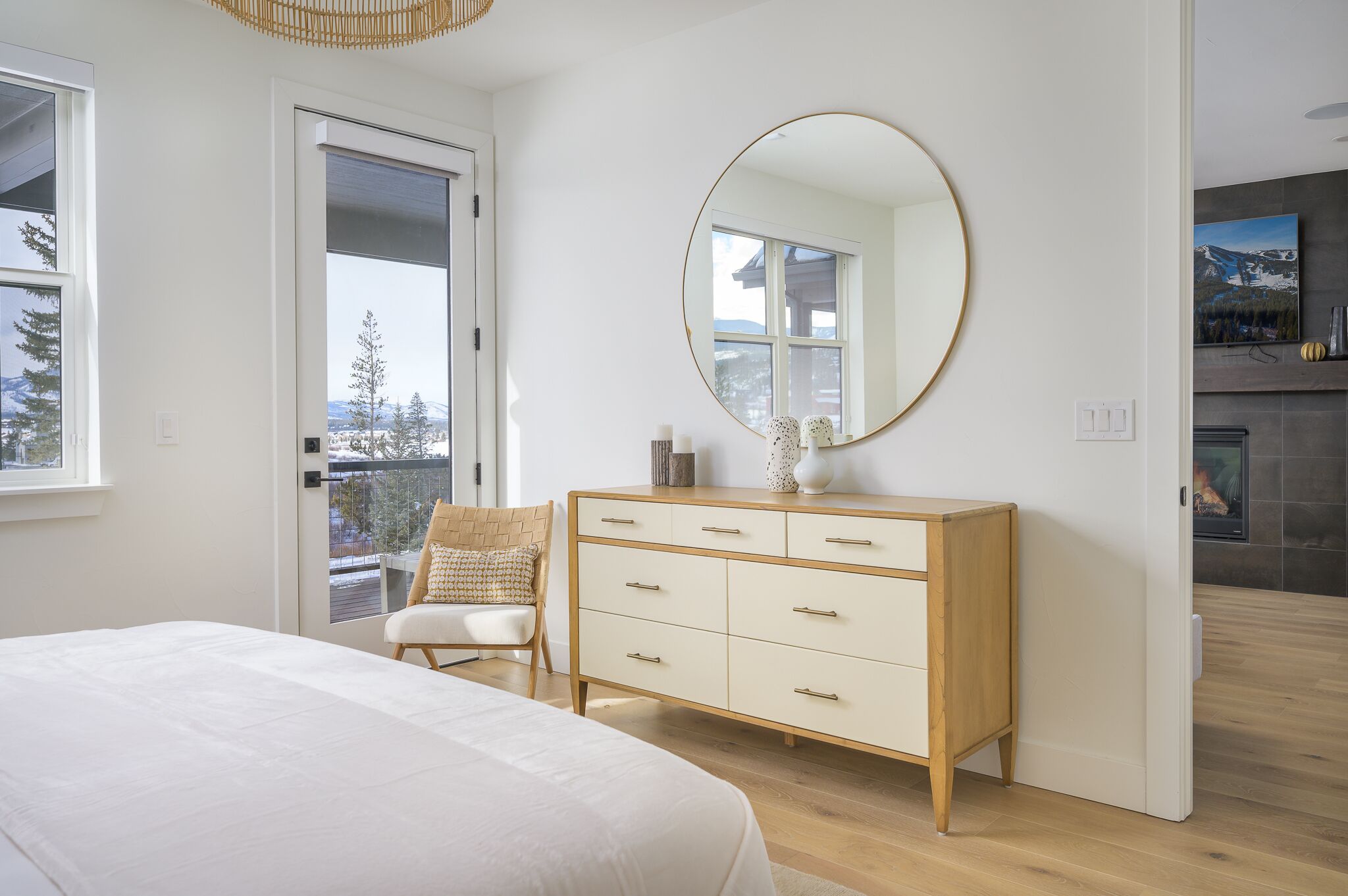 Un dormitorio con cama, cómoda, silla, un espejo grande y chimenea.