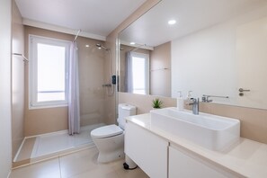Enjoy a refreshing shower in the walk-in shower with a glass door, a standalone toilet, and a spacious vanity with a mirror.