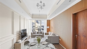 Uma sala de jantar moderna com uma mesa posta para quatro pessoas, um lustre e vista da cidade através de grandes janelas.