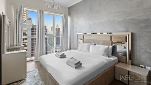 Quarto moderno com uma cama grande, vista da cidade e parede cinza com textura.