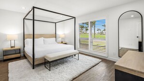 Une chambre à coucher moderne avec un lit à baldaquin, des tables de chevet avec des lampes, une grande fenêtre avec des stores et un miroir.