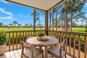 A covered outdoor seating area with a table and chairs, overlooking a golf course. - New Home on PGA Golf Course by Guaranteed Rental™ (Palm Beach Gardens)