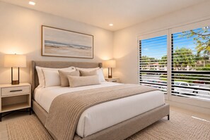 A modern bedroom with a large bed, two bedside tables, a nightstand, a window with blinds, and a painting on the wall. - New Home on PGA Golf Course by Guaranteed Rental™ (Palm Beach Gardens)