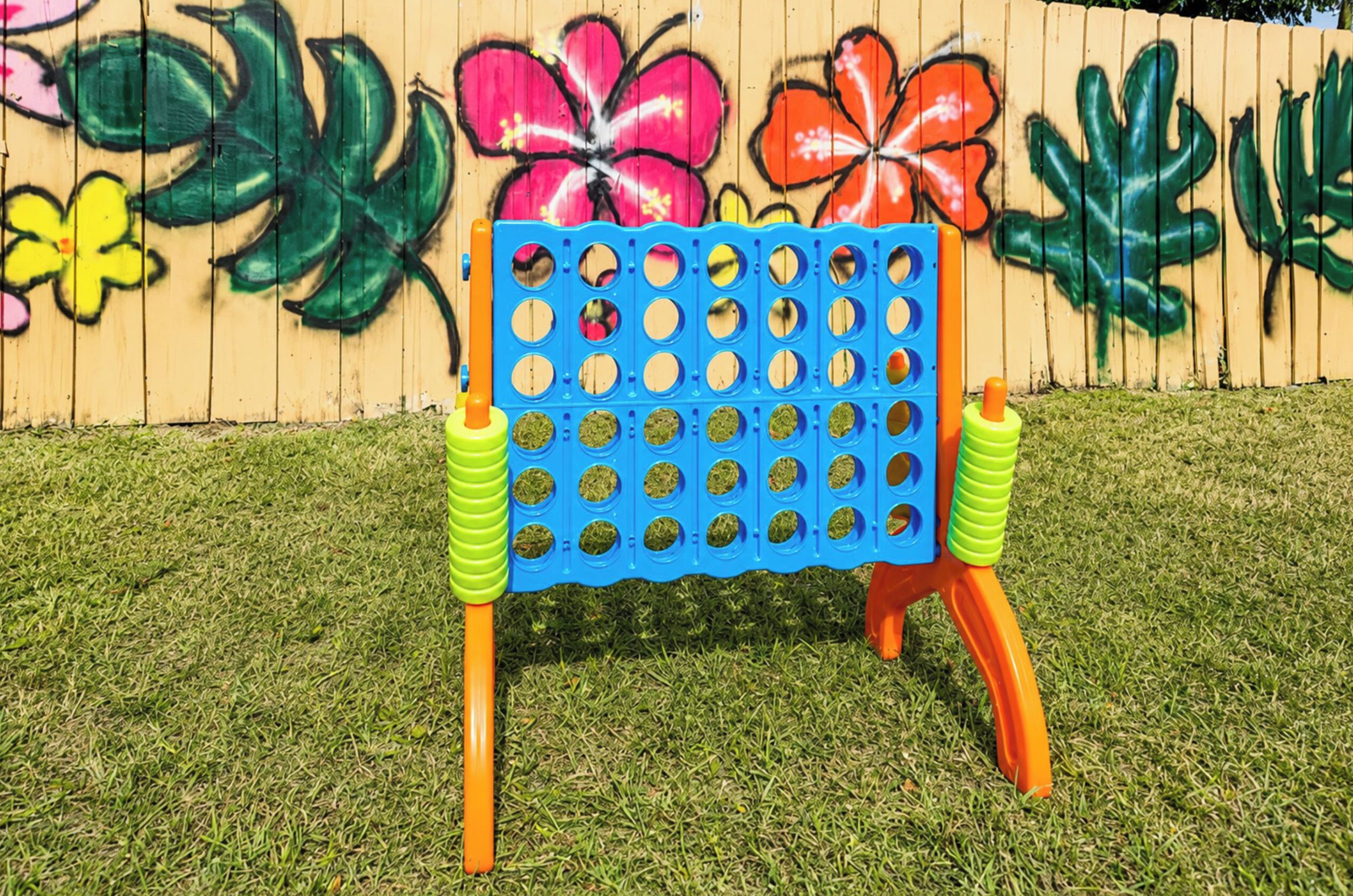 Une chaise bleue et orange, dont le dossier est percé de trous, est placée sur une pelouse.