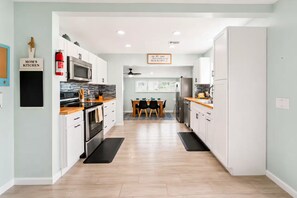 A modern kitchen with white cabinets, a microwave, stove, and a dining area with a table and chairs.