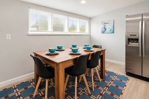 A dining area with a wooden table, four chairs, and blue bowls on plates.