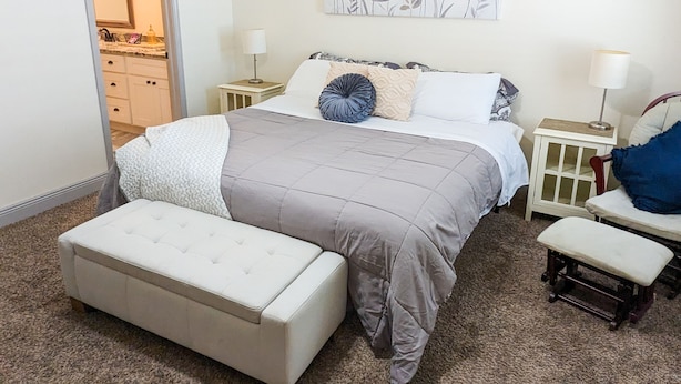 Ein Schlafzimmer mit einem Bett, Nachttischen, einer Bank und einem Gemälde an der Wand.