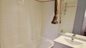 A bathroom with a bathtub, a sink, and a mirror.
