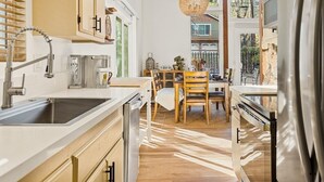 A modern kitchen with a large sink, wooden cabinets, and a dining area with a table and chairs.